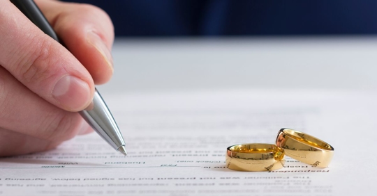 Someone signing document with two rings