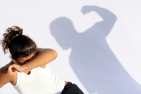 woman covering face and shadow of attacking man