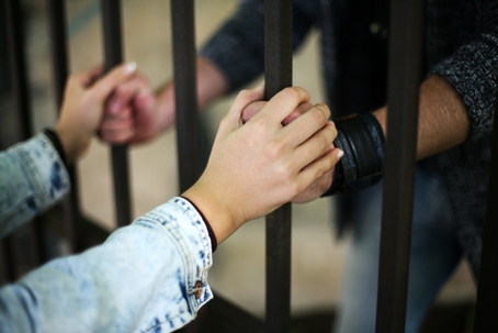 two people holding hands between jail cell bars