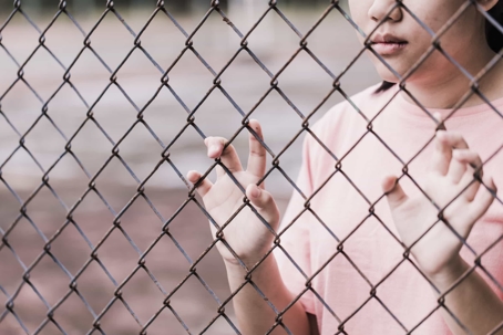 a woman standing behind a fence