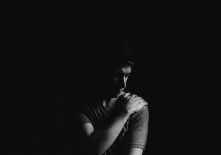 man in darkness holding shoulder
