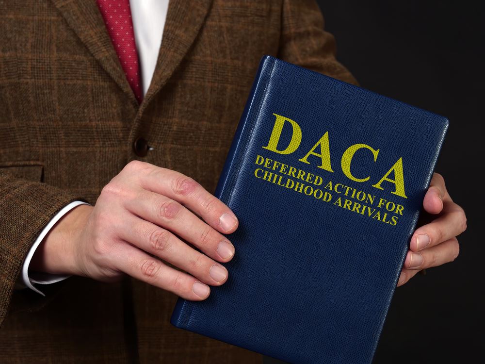 DACA document held by a man in a suit, emphasizing Deferred Action for Childhood Arrivals, relevant to discussions on immigration and DUI consequences for DACA recipients.